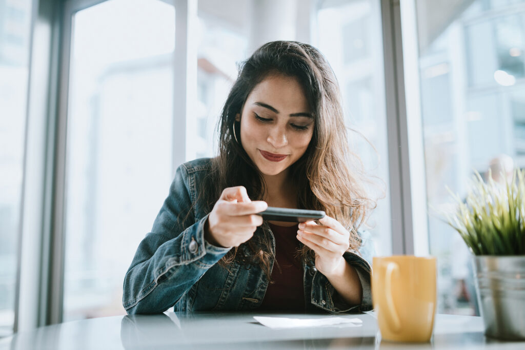 girl in cafe taking picture on phone