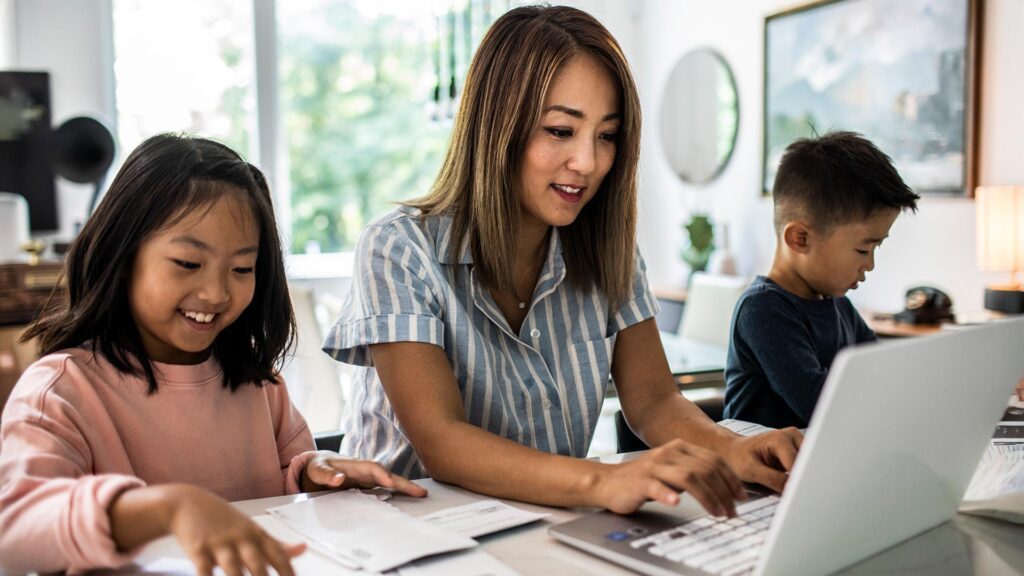 Mom paying bills at home with kids playing in the background