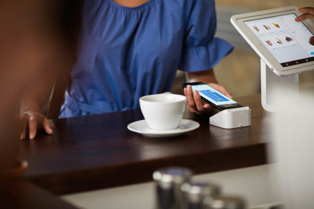 Woman making mobile payment at coffee shop