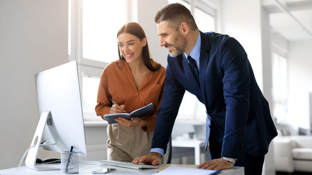 Business colleagues looking at computer and taking notes