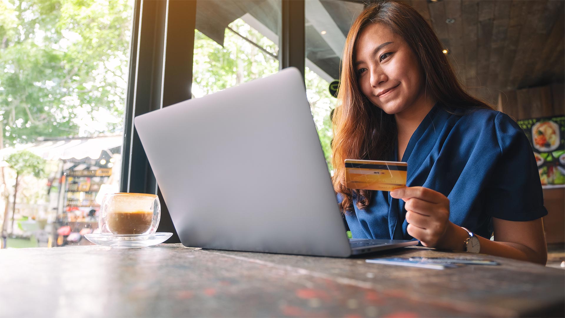Closeup image of a business woman holding credit card while using laptop computer