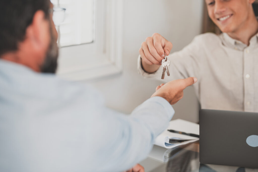 Crop close up of realtor give keys to man buyer or renter buying first home from agency.