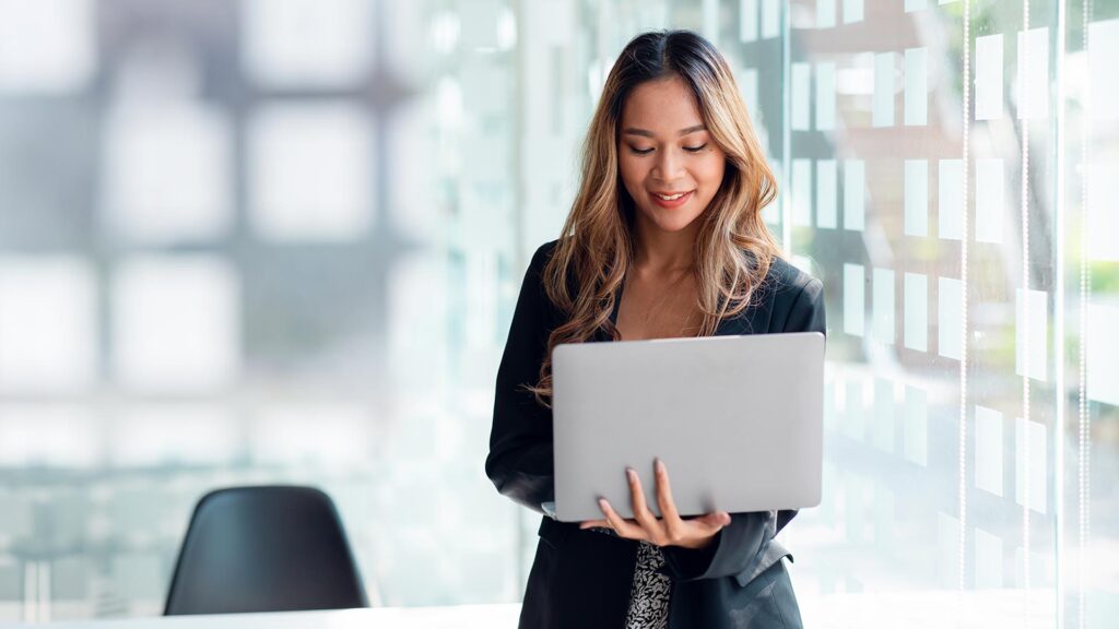 Excited happy Asian woman looking at the laptop screen, celebrating an online win