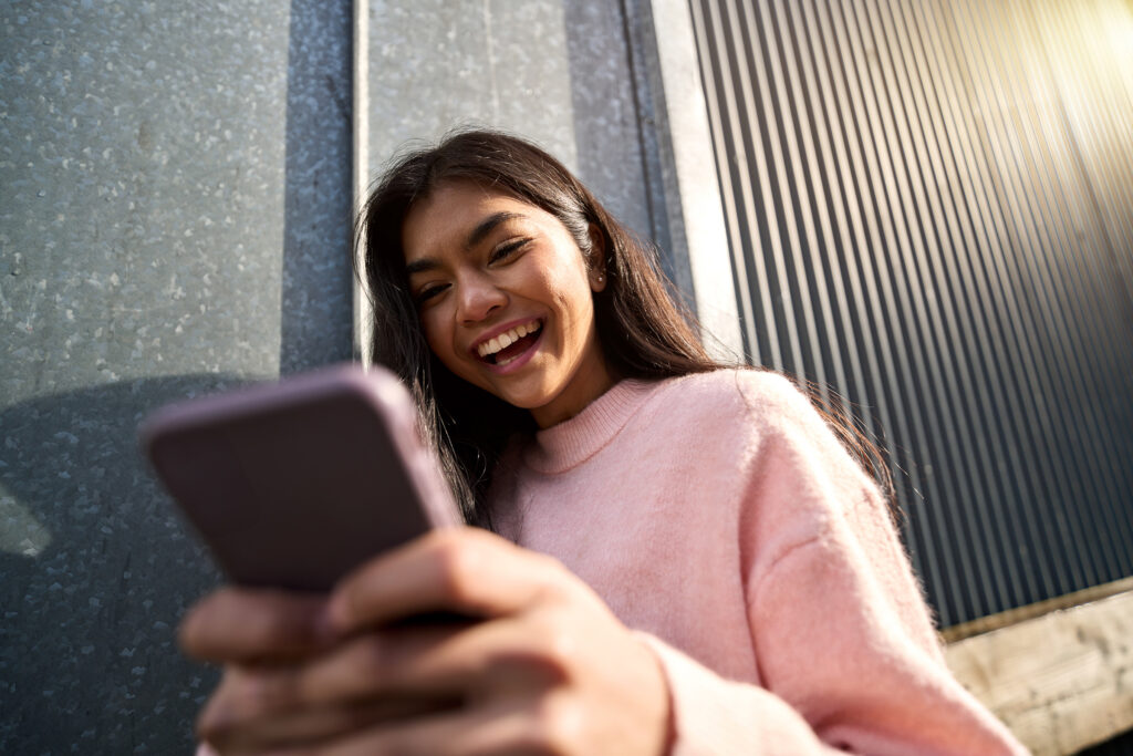 happy cheerful asian teen girl using mobile phone