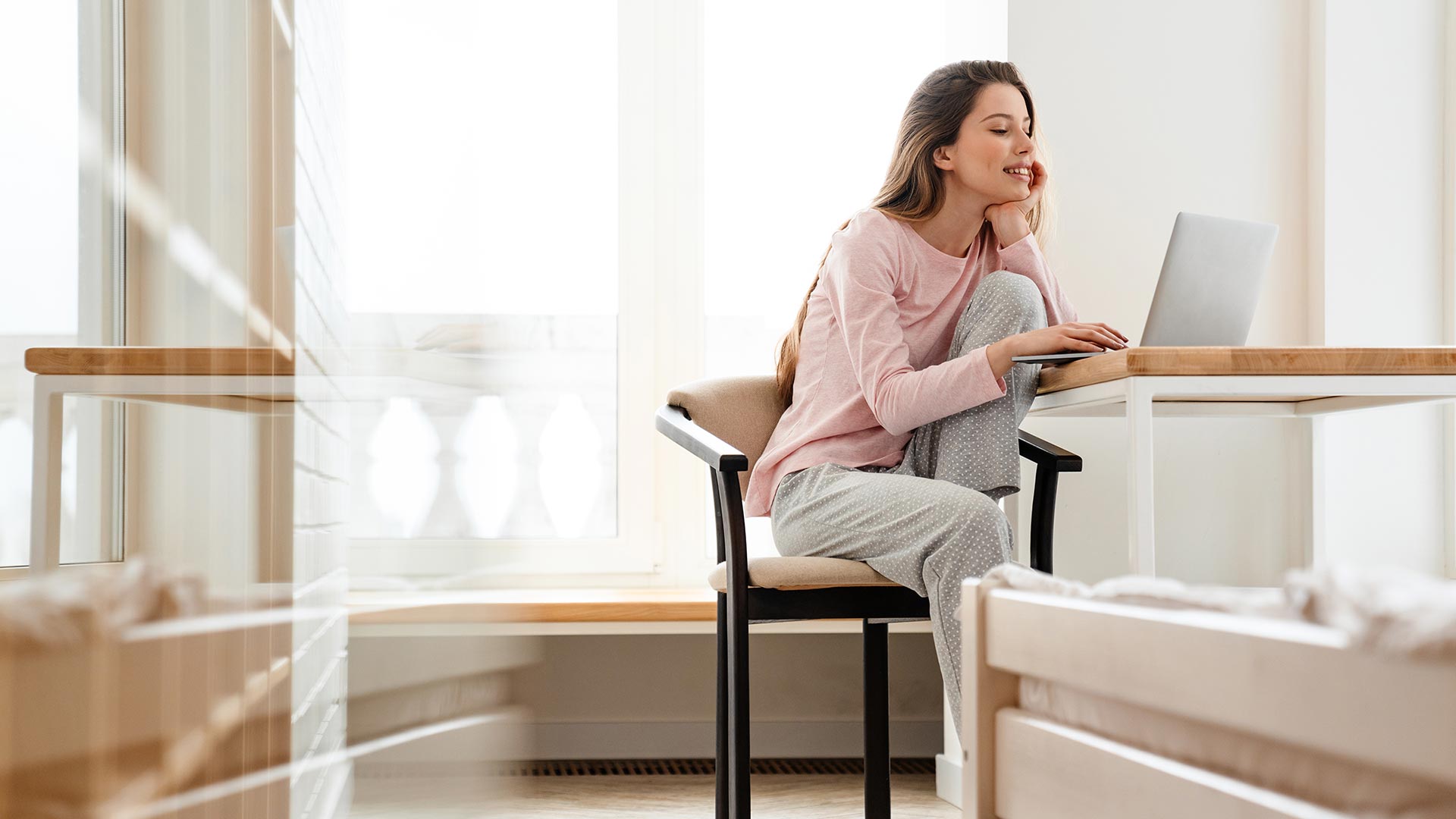 Happy young woman wearing lounge clothes using computer at home