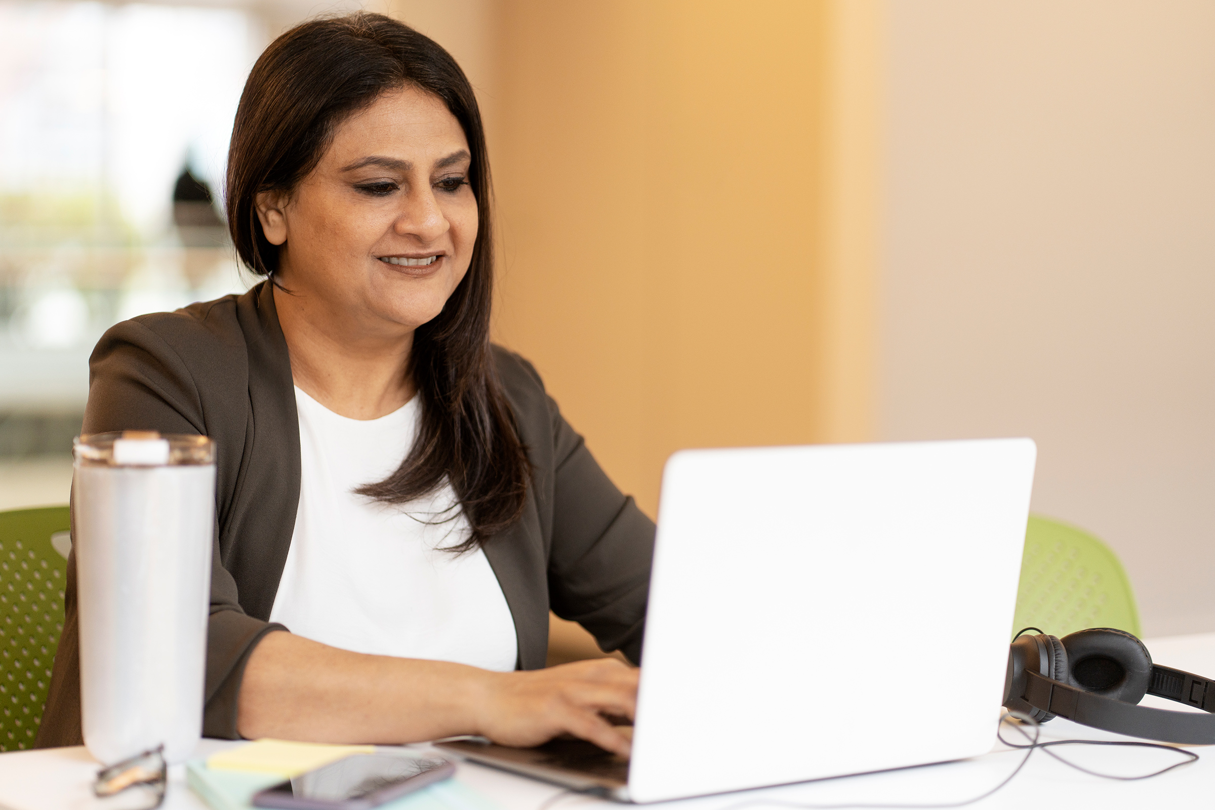Indian businesswoman using laptop computer, working online sitting in modern office