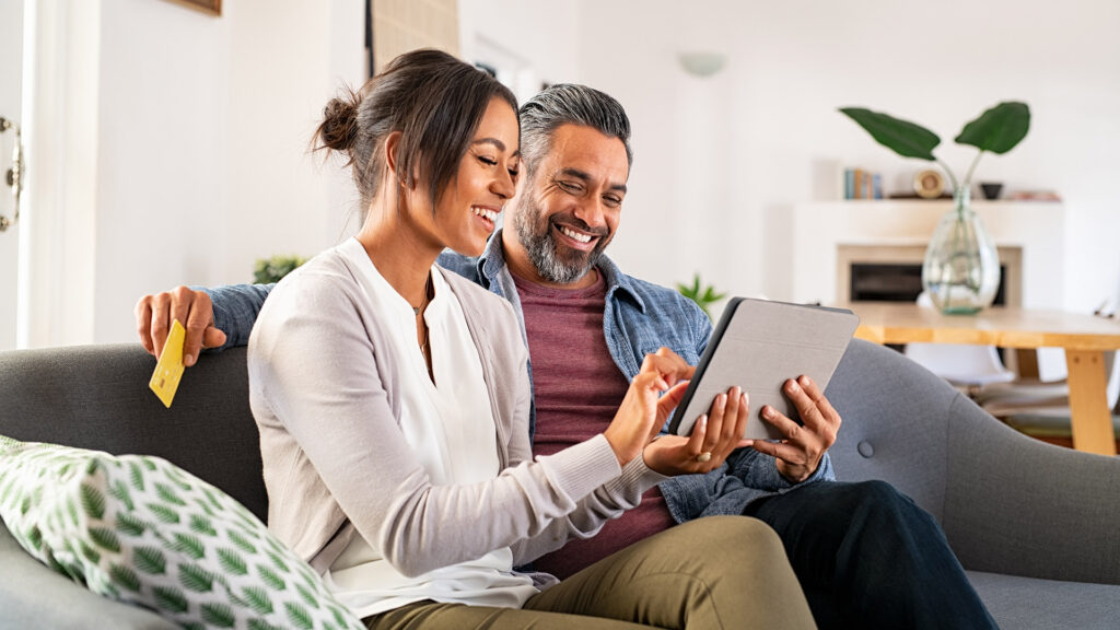Multi-ethnic adult couple makes payment on tablet