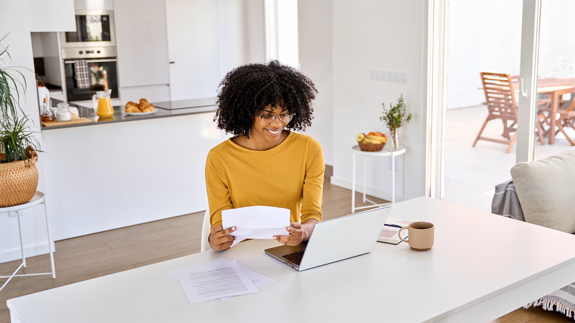 Happy African American young woman using laptop sitting at home table