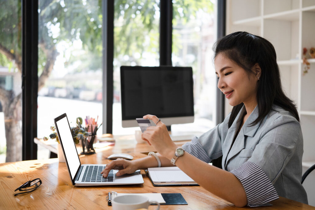 Young woman holding credit card making an online purchase